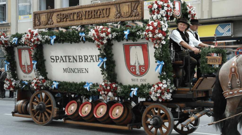 Spatenbrau carriage during the Oktoberfest parade. The carriage is led by horses and is covered in blue & white ribbons and red and white flowers
