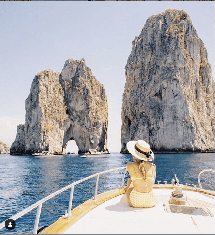 photo of the famous rocks in capri italy with young woman in bikini on a boat; image from instagrammer @darlingcoco