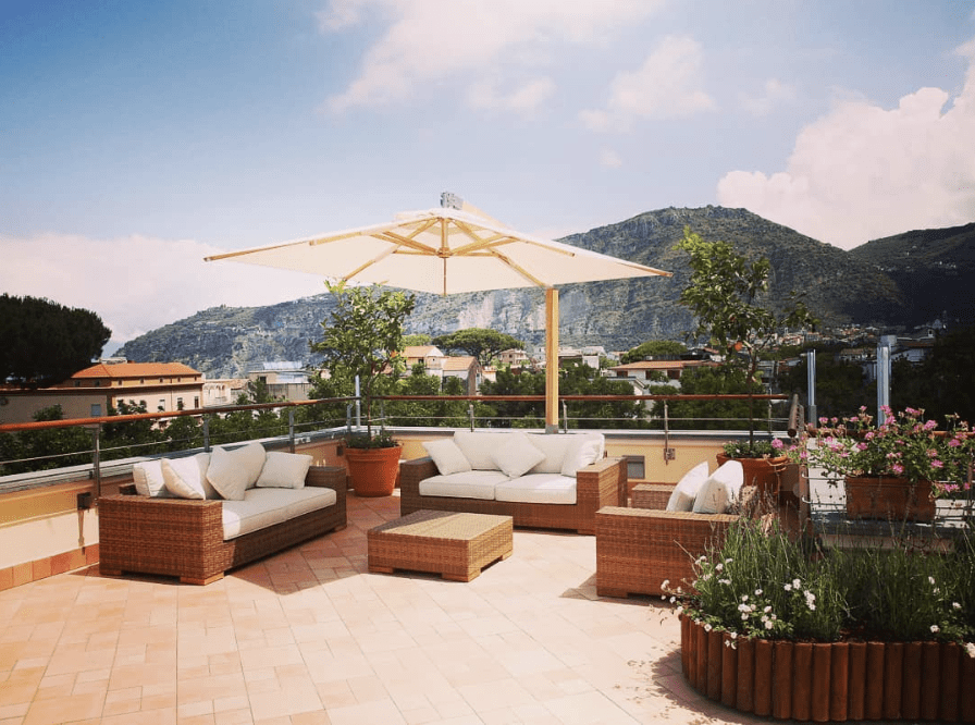 Rooftop with three outdoor couches with white pillows and potted plants.