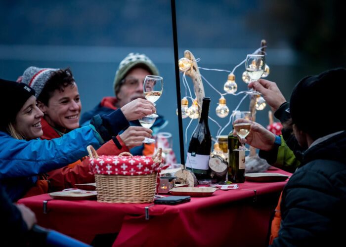 Group of students traveling with bus2alps and enjoying a traditional raclette dinner in Interlaken on a sunset dinner float with Outdoor.ch