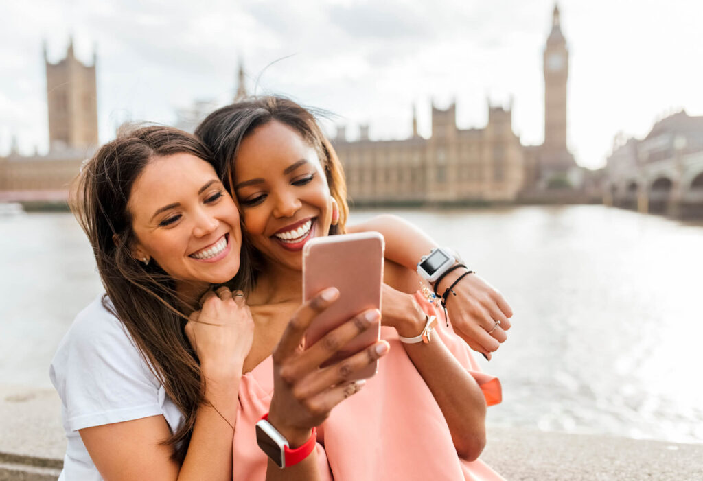 Two women taking a selfie across the River Thames from Big Ben in London